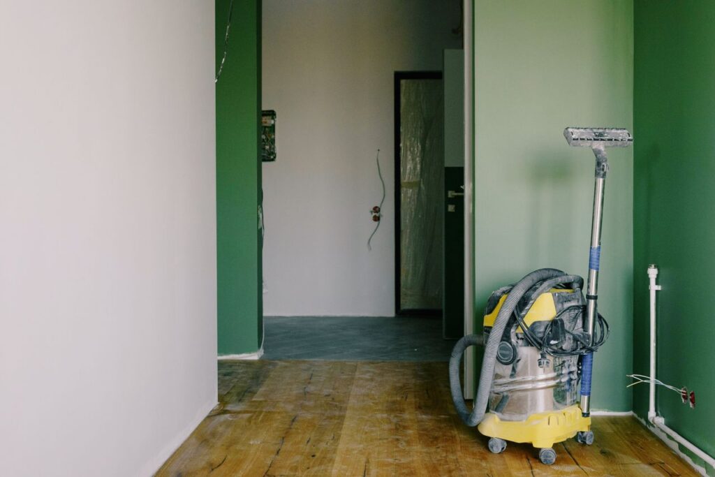 Demo Post 3 Industrial vacuum cleaner placed on dirty parquet in room with green walls and doorway in spacious apartment during repair works